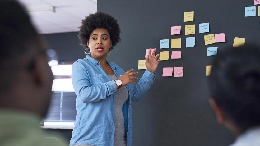 Instructor teaching at front of class pointing to post it notes